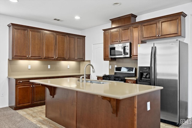 kitchen featuring light hardwood / wood-style floors, sink, stainless steel appliances, and a kitchen island with sink