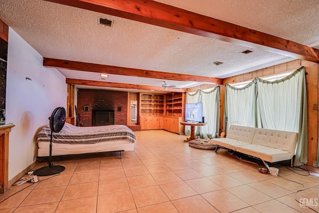 bedroom with light tile patterned floors, beamed ceiling, a fireplace, and a textured ceiling