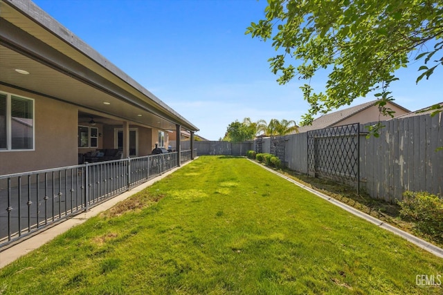 view of yard featuring a fenced backyard and a ceiling fan
