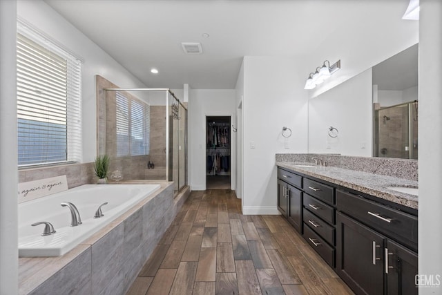 bathroom with double vanity, visible vents, a sink, a bath, and a stall shower