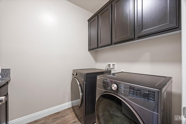 washroom with cabinet space, wood finished floors, baseboards, and separate washer and dryer