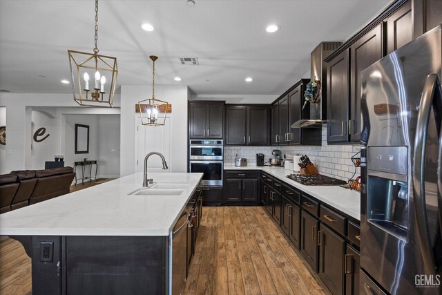 kitchen with light wood finished floors, stainless steel appliances, backsplash, visible vents, and a sink