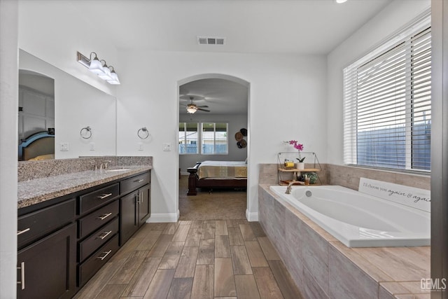 bathroom featuring ensuite bath, a ceiling fan, vanity, and visible vents