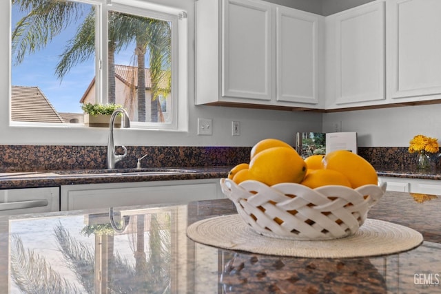 kitchen with white cabinets, a sink, and dark stone countertops