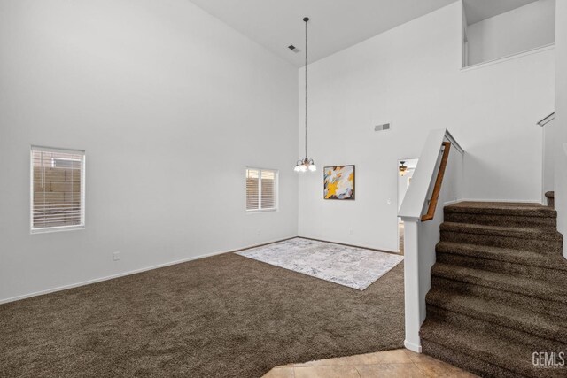carpeted foyer entrance with stairs, high vaulted ceiling, and visible vents
