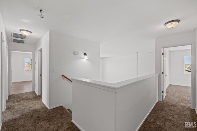hallway with baseboards, visible vents, an upstairs landing, and carpet floors