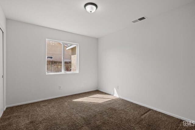 carpeted spare room featuring baseboards and visible vents