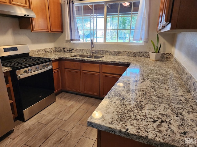 kitchen featuring light stone counters, sink, and stainless steel gas stove