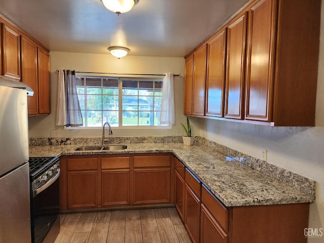 kitchen with stainless steel appliances, light stone countertops, and sink