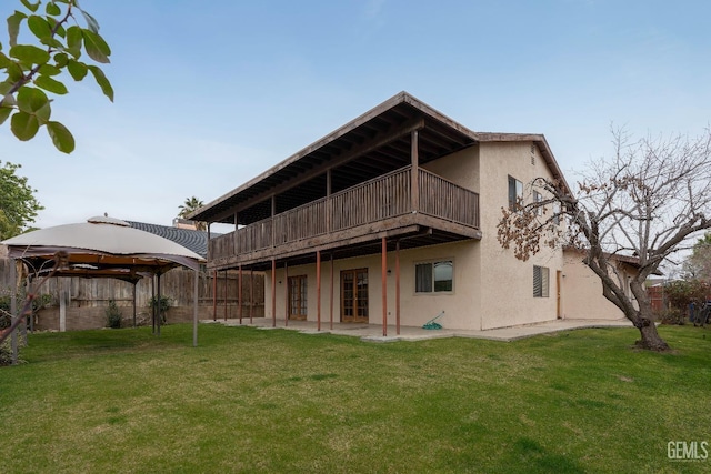 rear view of property with a gazebo, a yard, a patio, and stucco siding