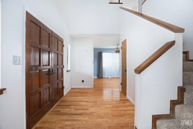 foyer entrance with stairs, a ceiling fan, light wood-style flooring, and baseboards