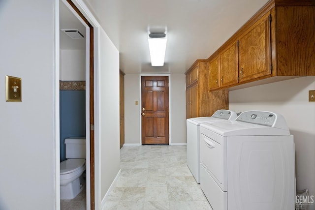 washroom with baseboards, cabinet space, visible vents, and washing machine and clothes dryer