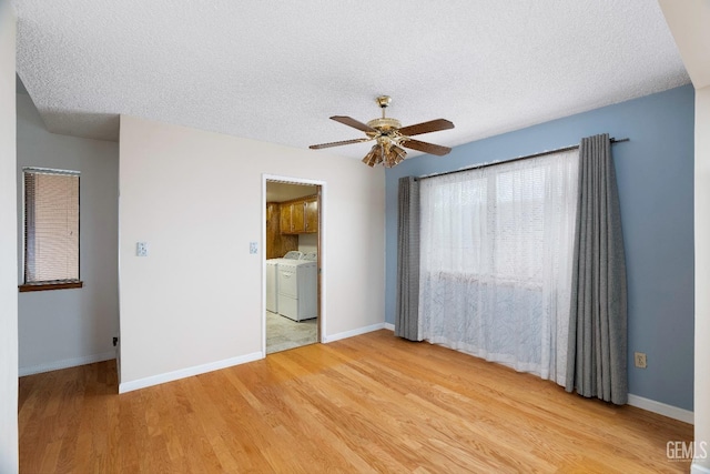 spare room featuring baseboards, a ceiling fan, a textured ceiling, washer and dryer, and light wood-type flooring