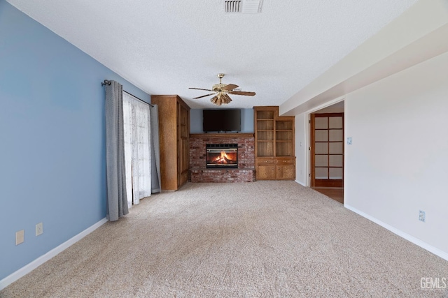 unfurnished living room with baseboards, visible vents, light colored carpet, a textured ceiling, and a fireplace