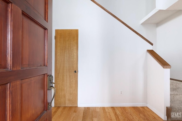 interior space featuring light wood-style floors, stairs, and baseboards