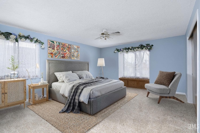 carpeted bedroom with a textured ceiling, visible vents, and a ceiling fan