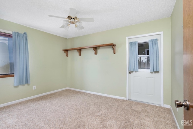 empty room featuring a ceiling fan, carpet flooring, a textured ceiling, and baseboards