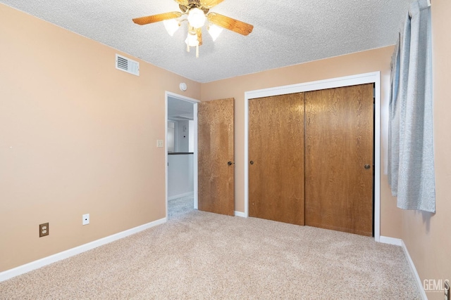 unfurnished bedroom with baseboards, visible vents, light colored carpet, a textured ceiling, and a closet