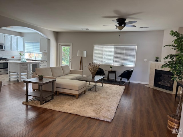 6720 Alderbrook Ln, Bakersfield, CA 93312 - living room with ceiling fan, arched walkways, dark wood finished floors, and a fireplace