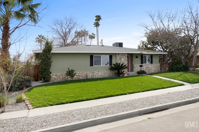 ranch-style home with roof with shingles, stucco siding, a front yard, fence, and stone siding