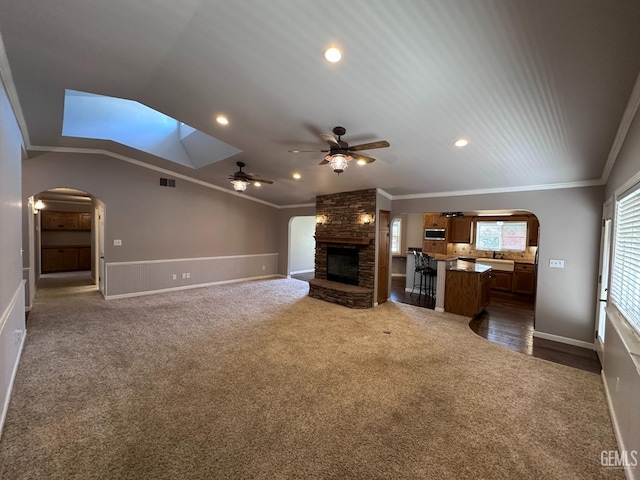 4049 Liz Dr, Bakersfield, CA 93312 - unfurnished living room with arched walkways, crown molding, dark colored carpet, a ceiling fan, and a fireplace
