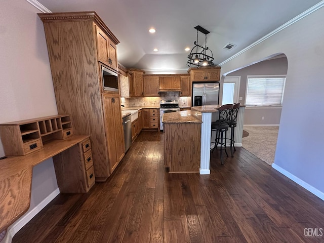 4049 Liz Dr, Bakersfield, CA 93312 - kitchen featuring appliances with stainless steel finishes, arched walkways, a kitchen bar, brown cabinets, and ornamental molding