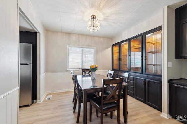 4401 Hughes Ln Unit 148, Bakersfield, CA 93304 - dining space featuring a chandelier, light wood finished floors, and a wainscoted wall