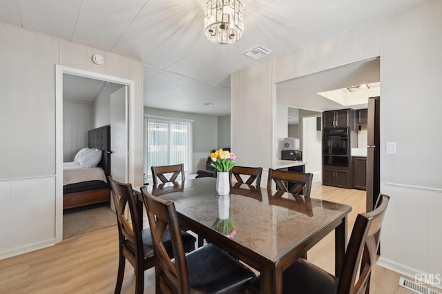4401 Hughes Ln Unit 148, Bakersfield, CA 93304 - dining area with a decorative wall, light wood-style floors, a chandelier, and a wainscoted wall