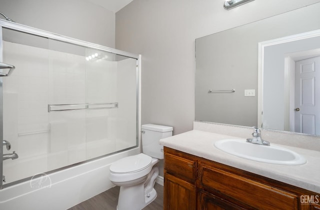 full bathroom with hardwood / wood-style flooring, bath / shower combo with glass door, toilet, and vanity