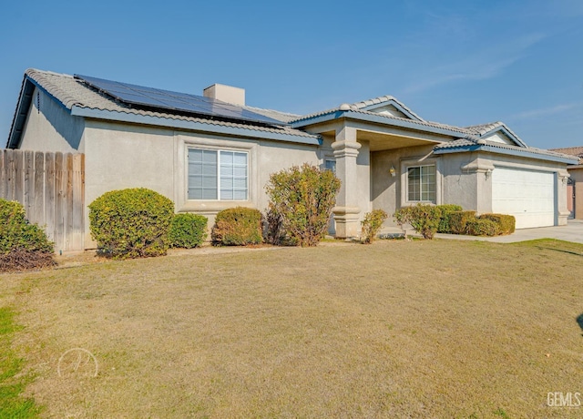 view of front facade with a garage, a front yard, and solar panels