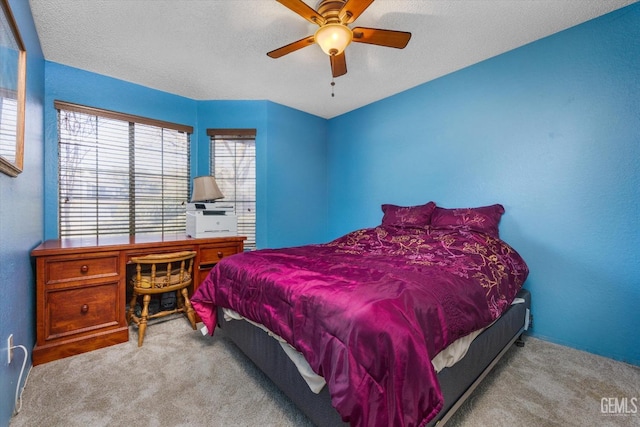 carpeted bedroom with ceiling fan and a textured ceiling