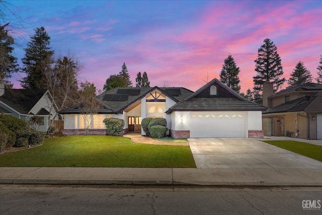 view of front of property featuring a yard, a garage, and solar panels