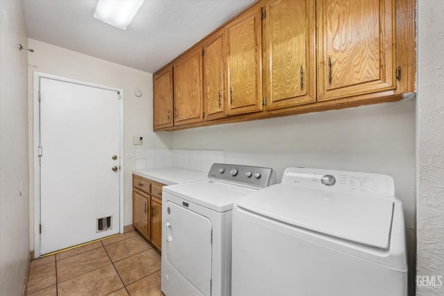 washroom featuring independent washer and dryer, cabinets, and light tile patterned floors