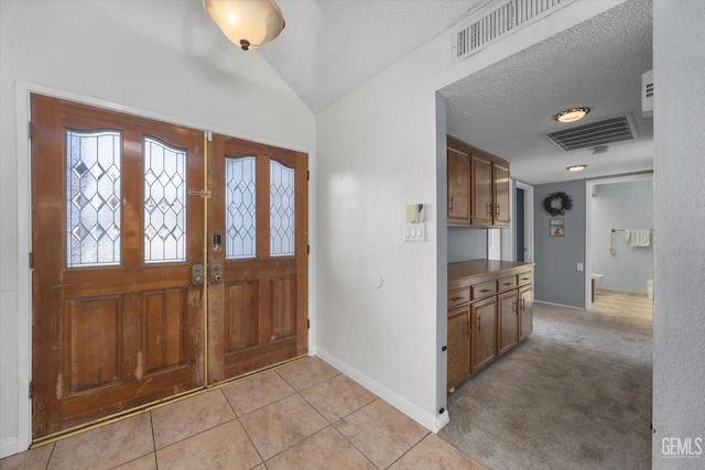 entryway with lofted ceiling, light tile patterned floors, and a textured ceiling