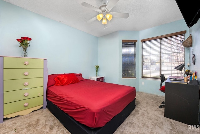 bedroom with ceiling fan, light colored carpet, and a textured ceiling