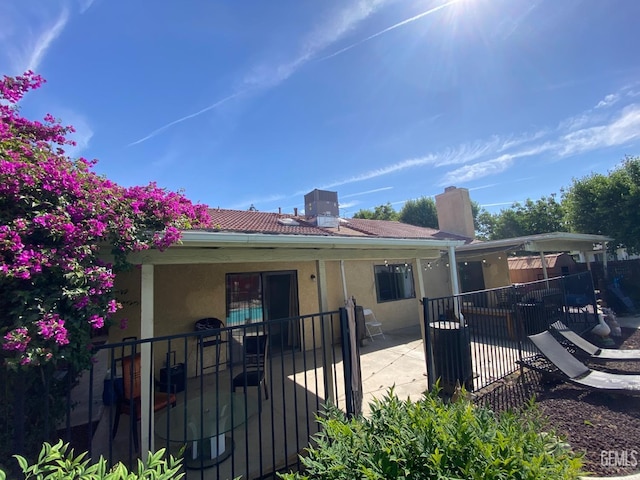 back of property featuring stucco siding, a chimney, fence, and a patio area