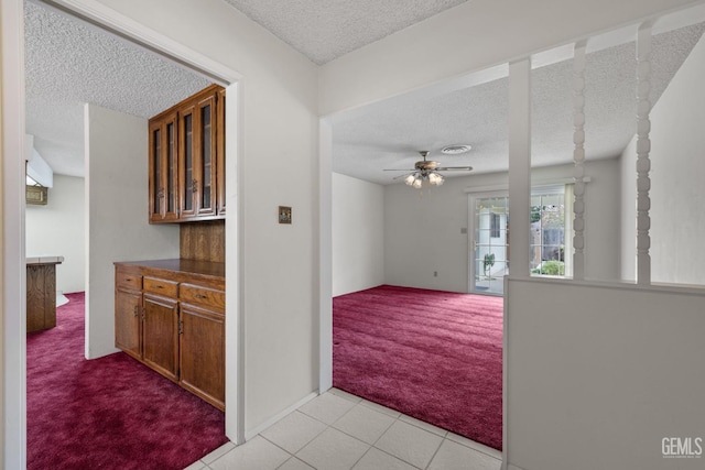 hall with light tile patterned floors, light colored carpet, and a textured ceiling