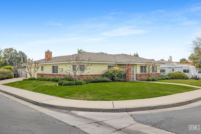 single story home featuring driveway, brick siding, a chimney, and a front yard