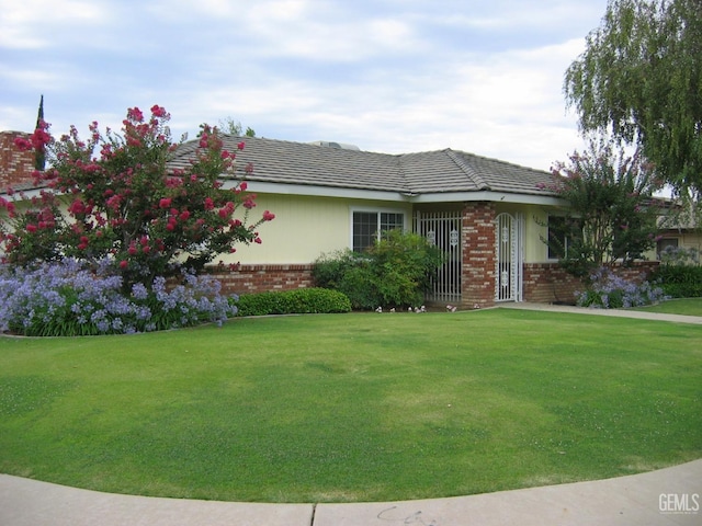 ranch-style house featuring a front yard and brick siding