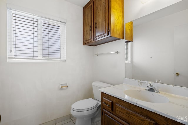 bathroom with tile patterned flooring, a healthy amount of sunlight, toilet, and vanity