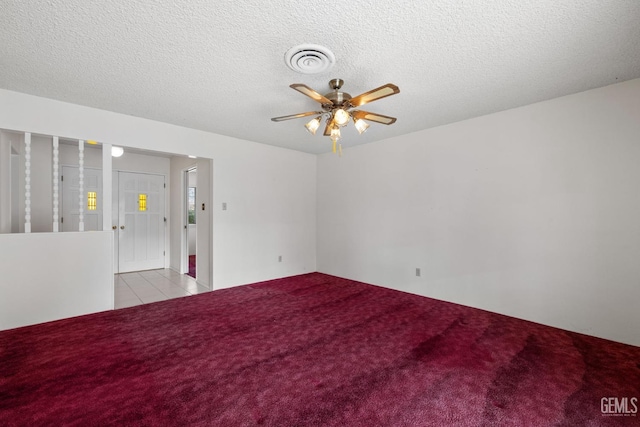 empty room featuring visible vents, light carpet, a textured ceiling, and ceiling fan