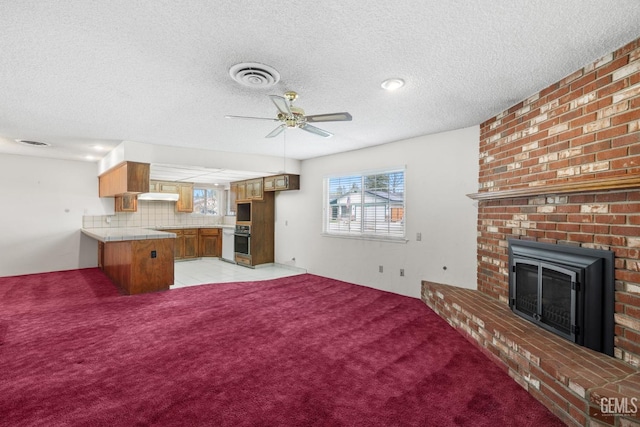 unfurnished living room with visible vents, a ceiling fan, a fireplace, and a textured ceiling