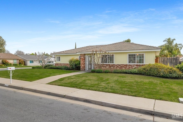 ranch-style house with brick siding, a front lawn, and fence