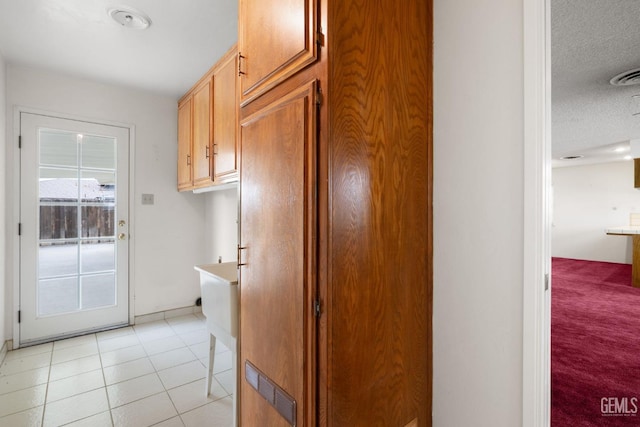 kitchen with light tile patterned floors, visible vents, a textured ceiling, and light countertops