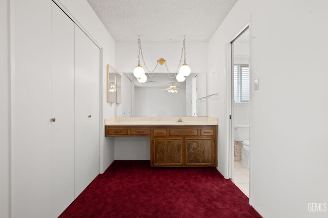 bathroom with vanity, a textured ceiling, carpet flooring, and toilet