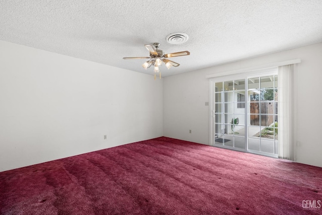 carpeted spare room featuring a textured ceiling, visible vents, and ceiling fan