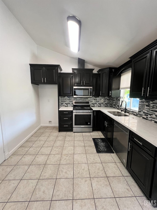 107 Coverdale Ct, Bakersfield, CA 93307 - kitchen featuring stainless steel appliances, dark cabinets, vaulted ceiling, and decorative backsplash