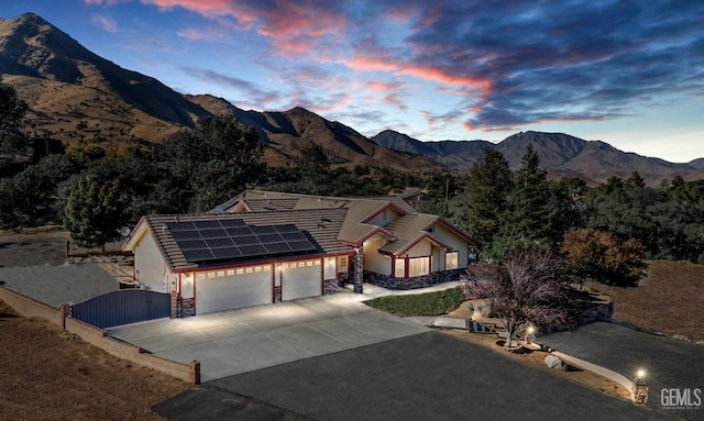 view of front of property featuring solar panels, a mountain view, and a garage