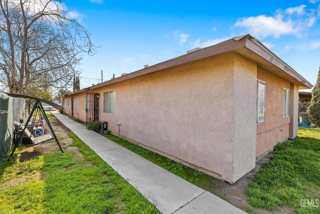 view of home's exterior with stucco siding and a lawn