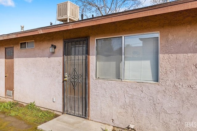 property entrance with central AC unit and stucco siding